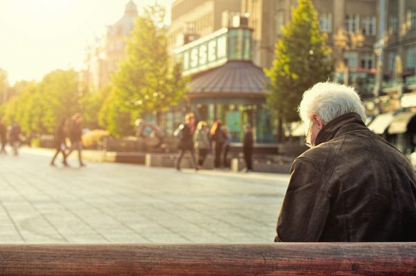 Retired man sitting on bench at building